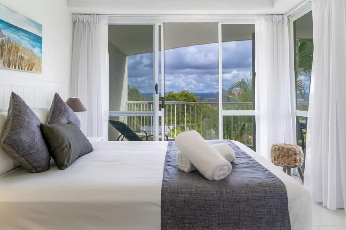 Une chambre d’hôtel avec un lit, une vue sur l’extérieur et un balcon.