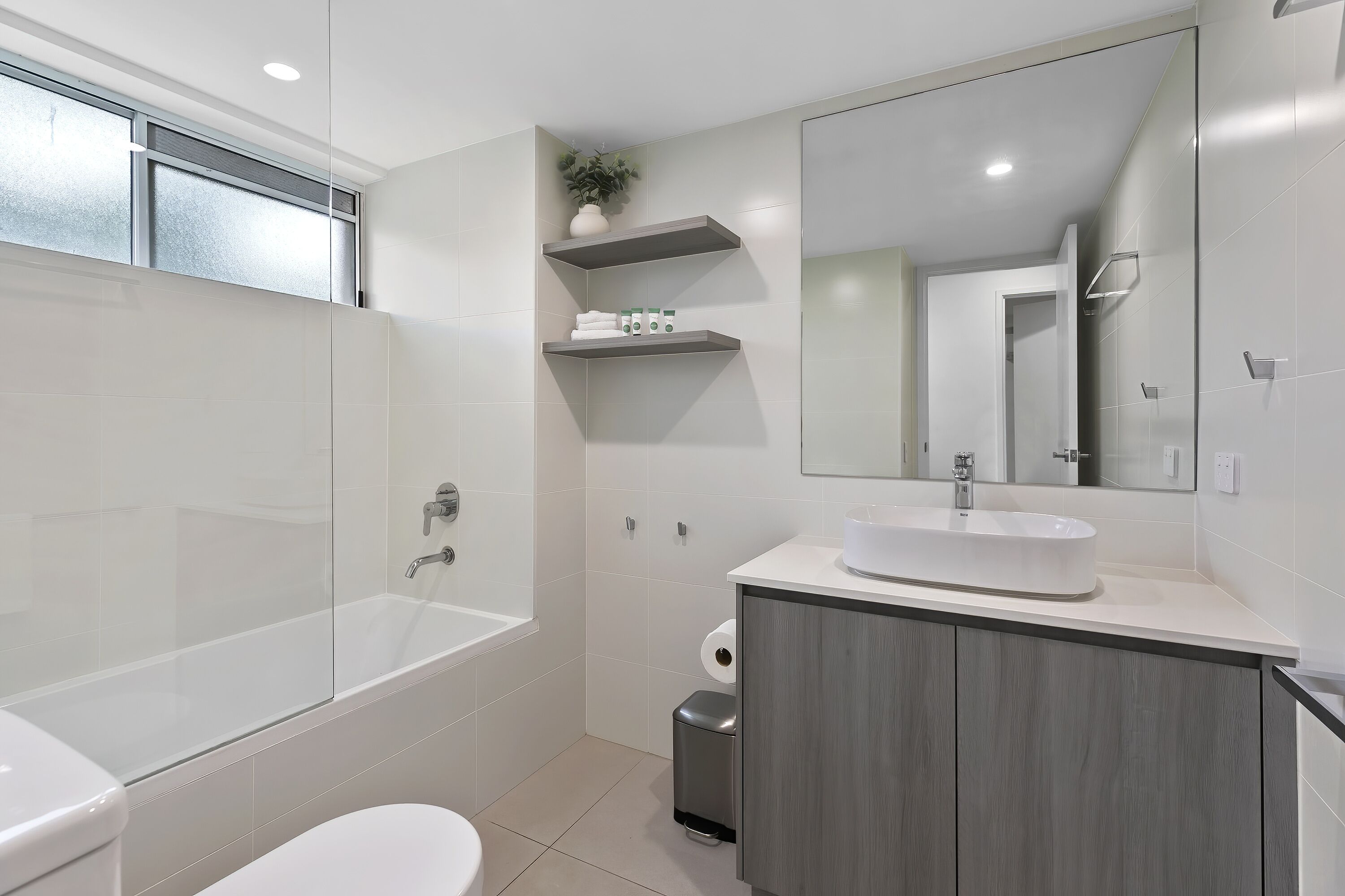Un baño moderno con bañera, inodoro, tocador con lavamanos y espejo.