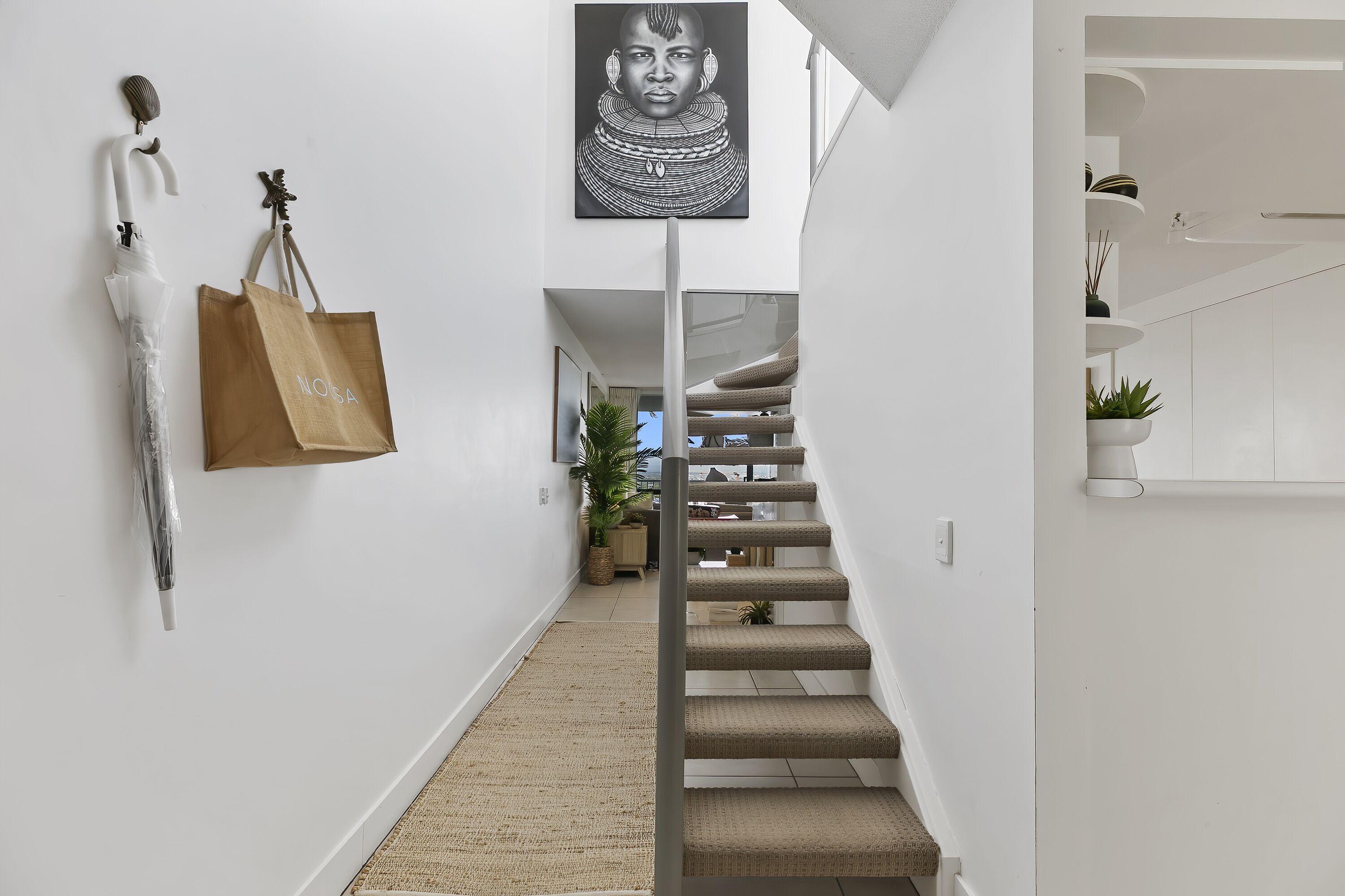 A modern interior with a staircase, a framed artwork, and a brown paper bag hanging on the wall.