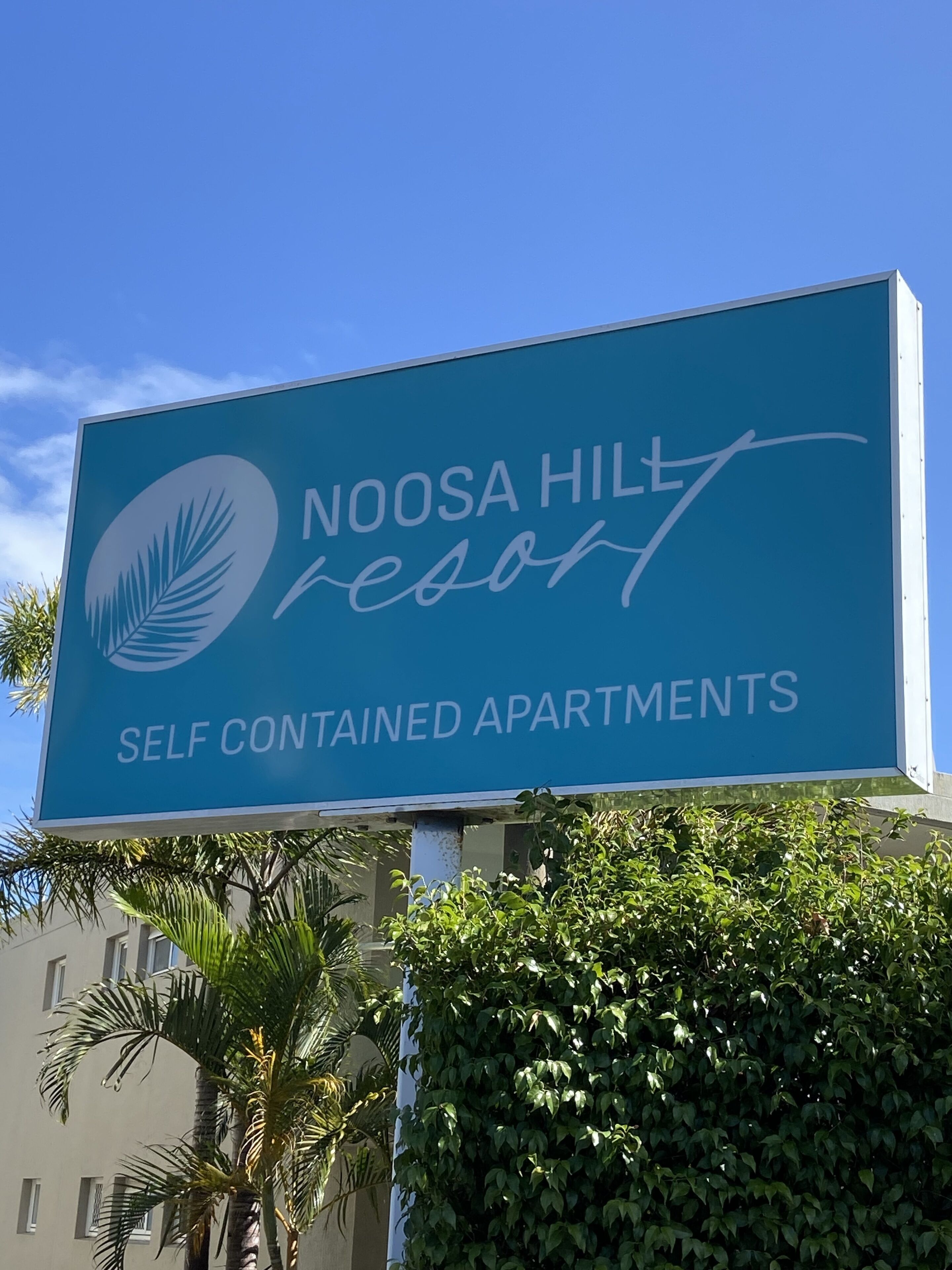 Une enseigne indiquant le Noosa Hill Resort et faisant la publicité d’appartements entièrement équipés.