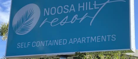 Naamplaatje voor Noosa Hill Resort, met advertentie voor volledig ingerichte appartementen.