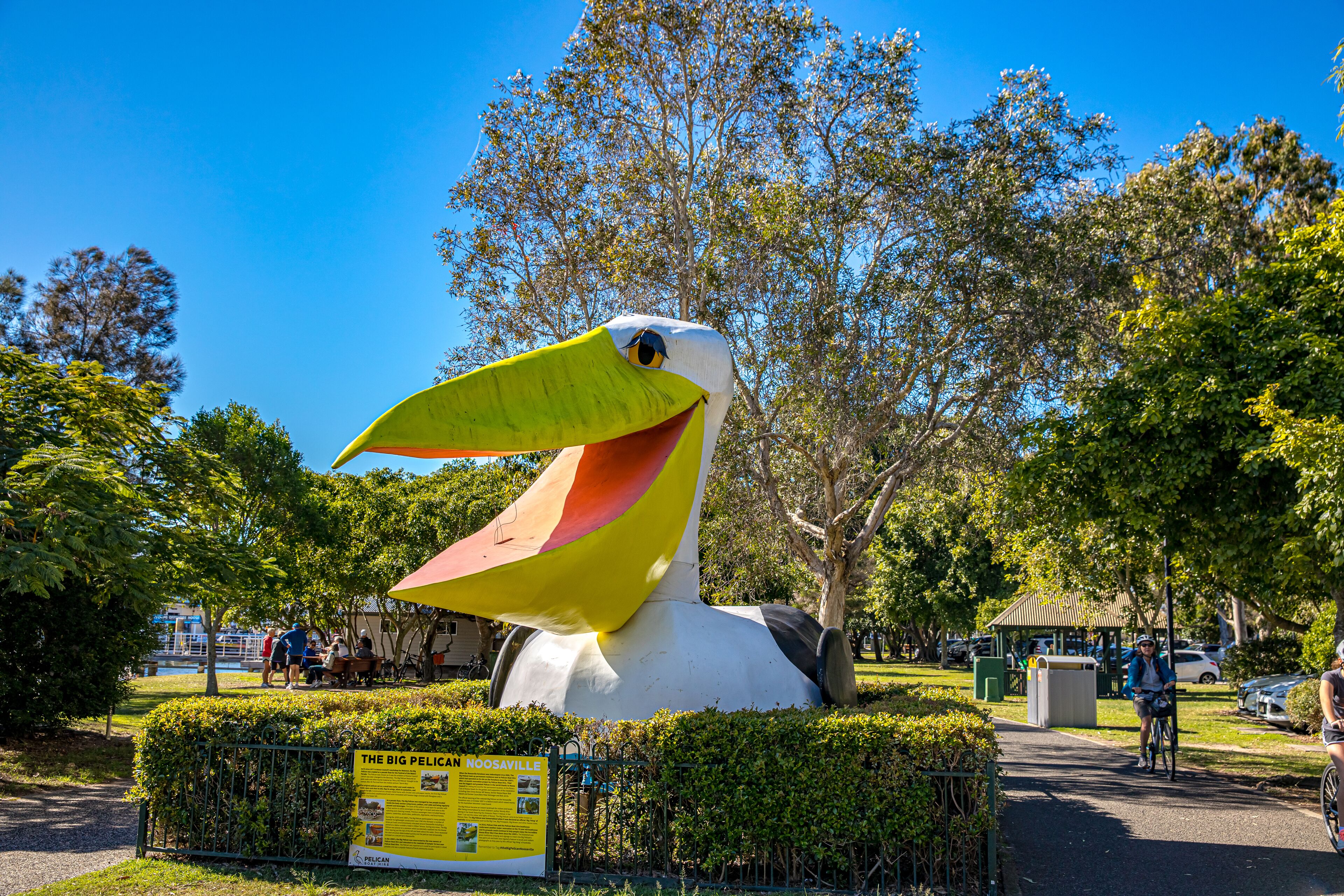 Eine große Pelikan-Skulptur in einem Park mit einem entsprechenden Schild.