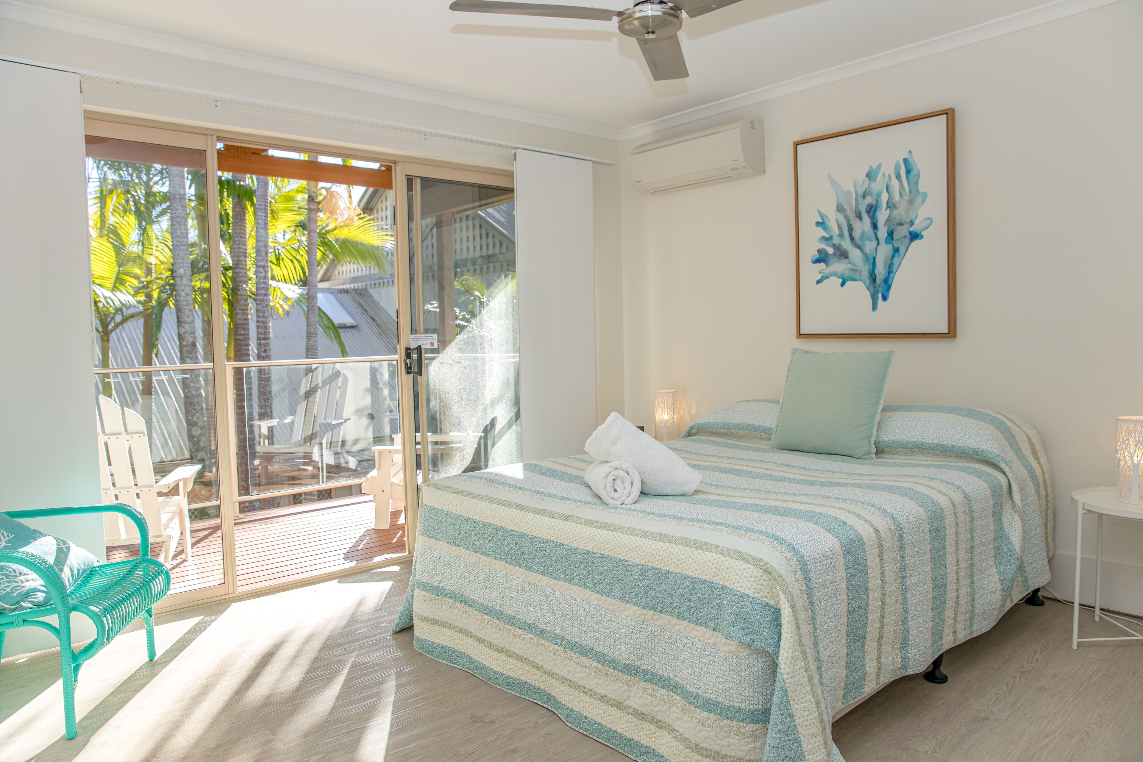A bedroom with a bed, a bench, and a view of the outdoors.