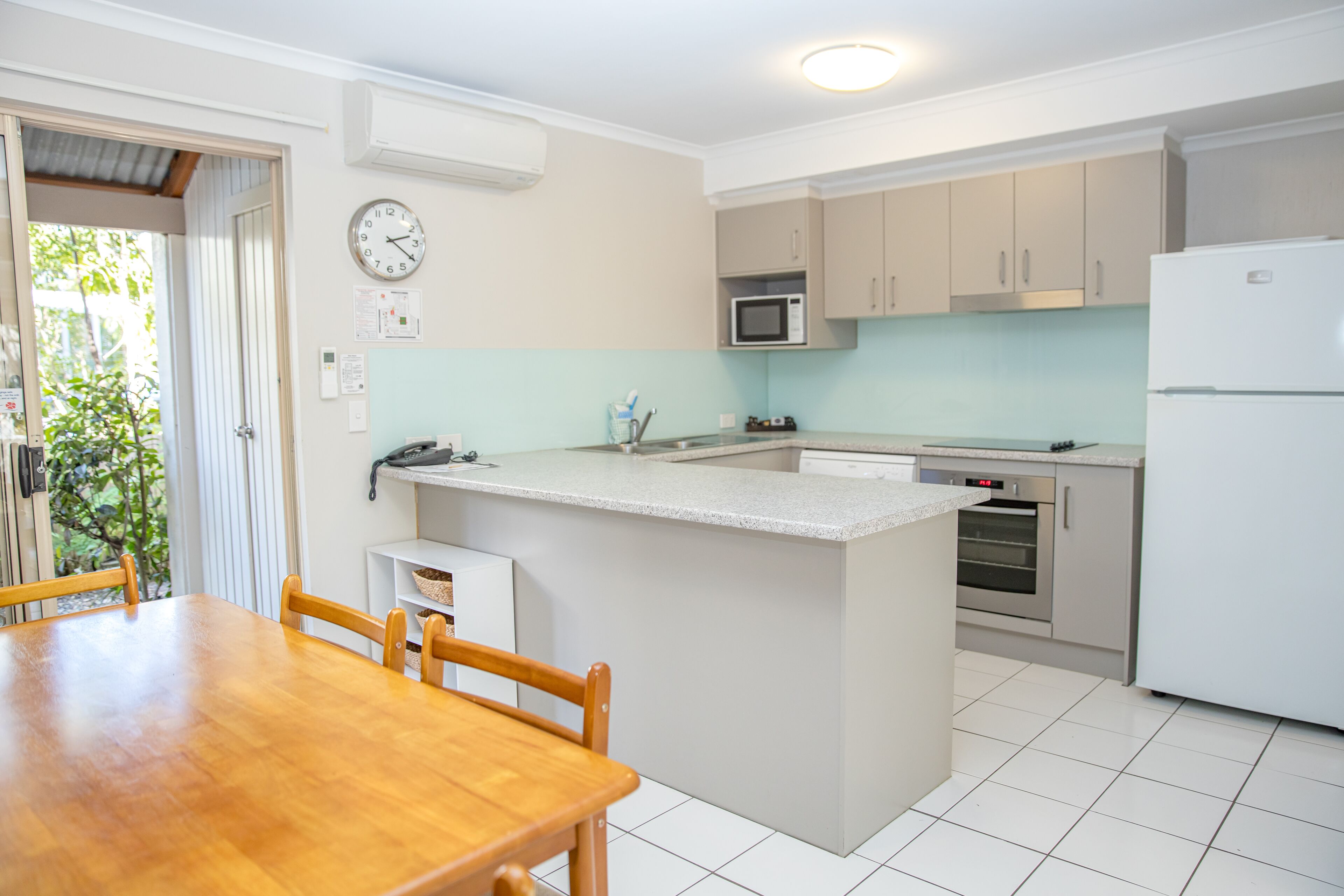 A kitchen with a wooden dining table, a microwave, an oven, and a refrigerator.