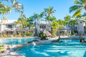 A resort with a swimming pool, palm trees, and modern buildings. - The Islander Noosa Resort (Noosaville)