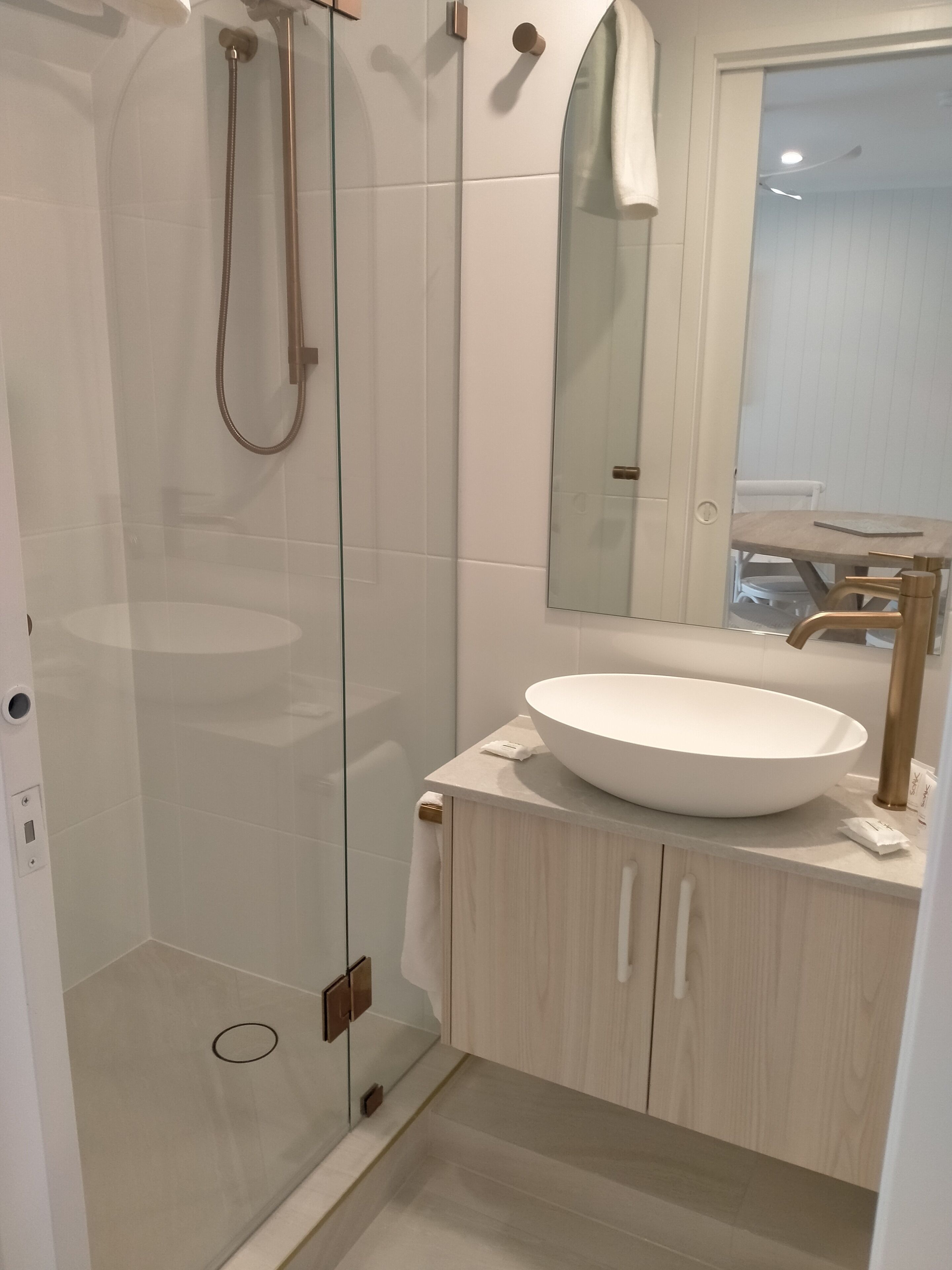 A modern bathroom with a glass-enclosed shower, a white sink, and a wooden vanity.