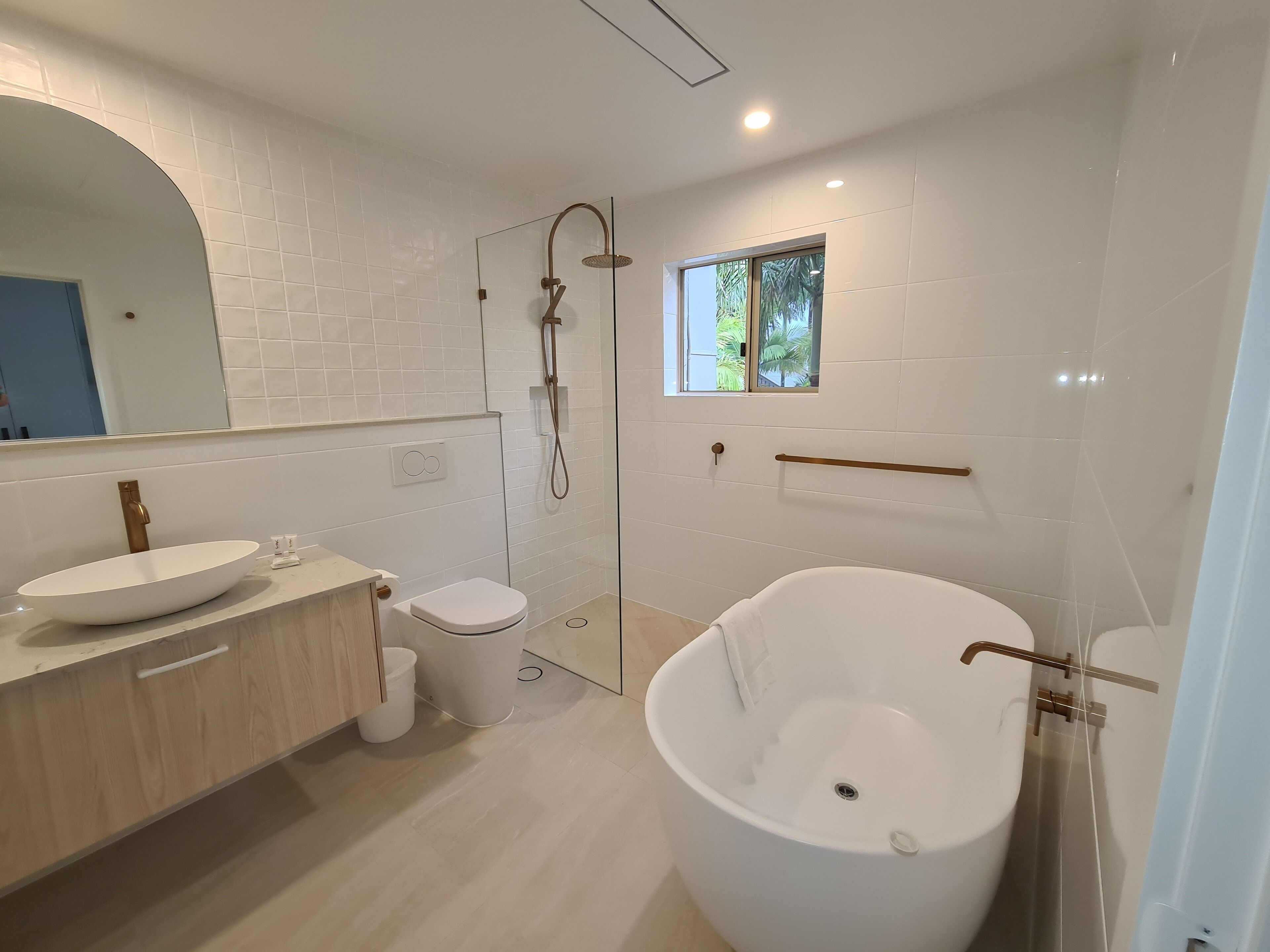 A modern bathroom with a freestanding bathtub, a glass-enclosed shower, a toilet, and a vanity with a sink.