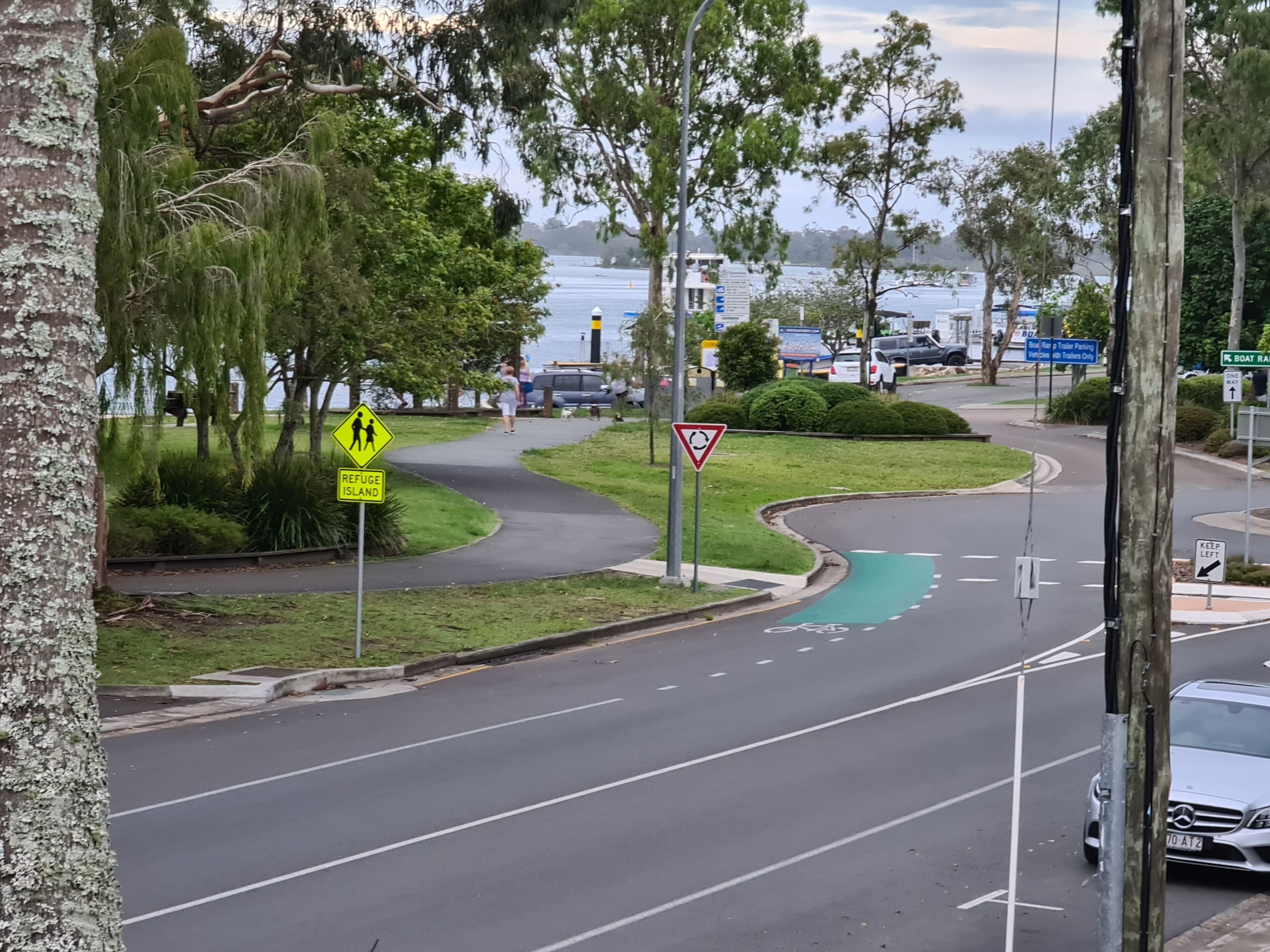 A road with a pedestrian crossing, a refuge island sign, and a keep left sign.