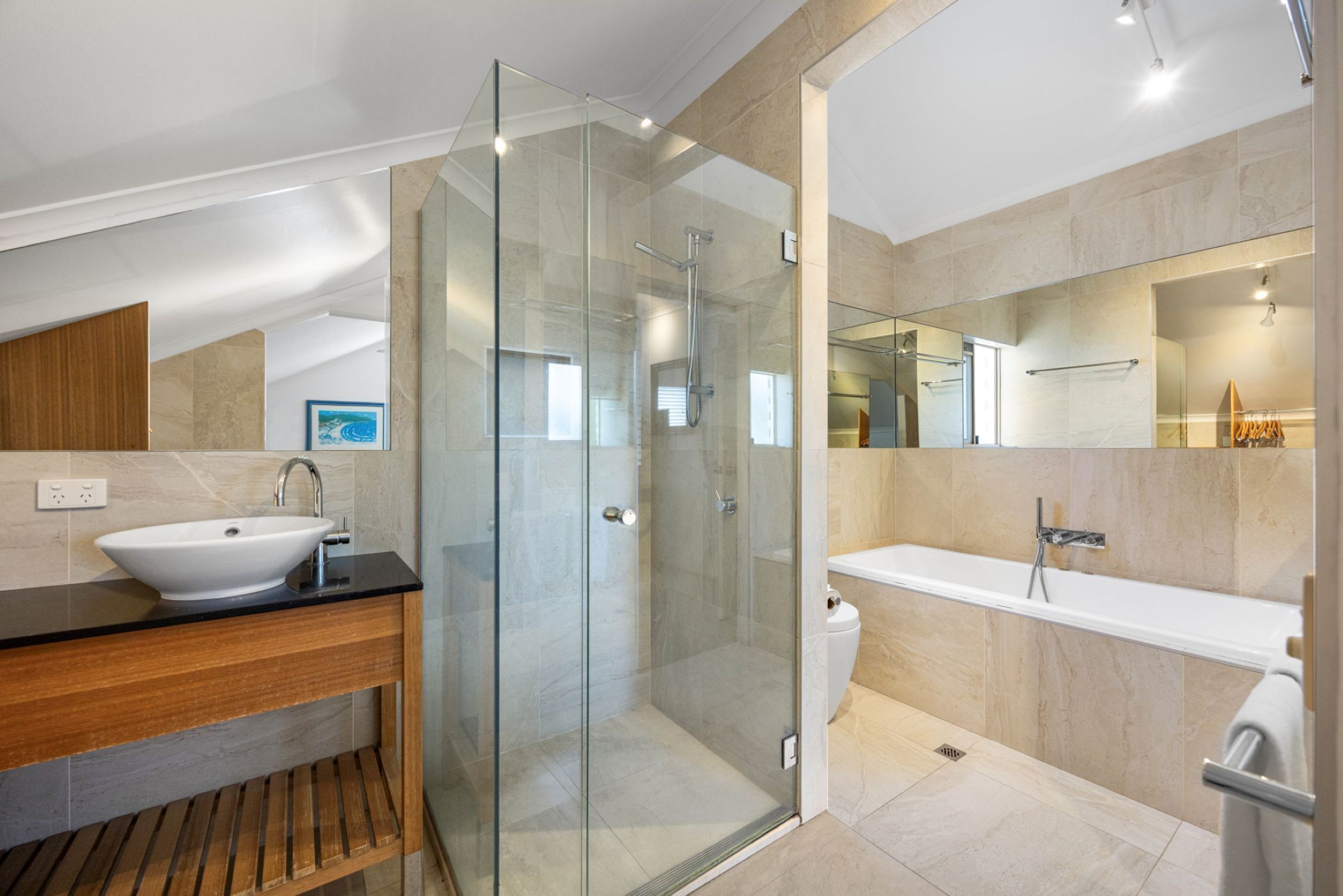 Une salle de bain moderne avec une douche à parois de verre, un lavabo blanc et un grand miroir.