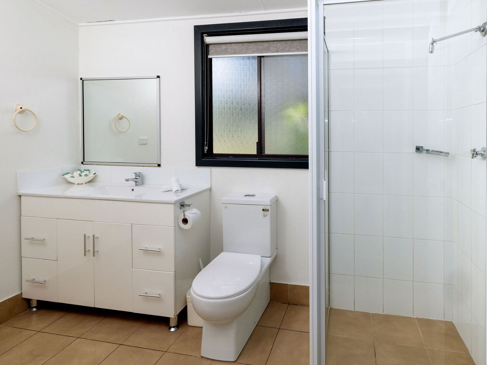 Un bagno con lavandino bianco, specchio, servizi igienici e una finestra.