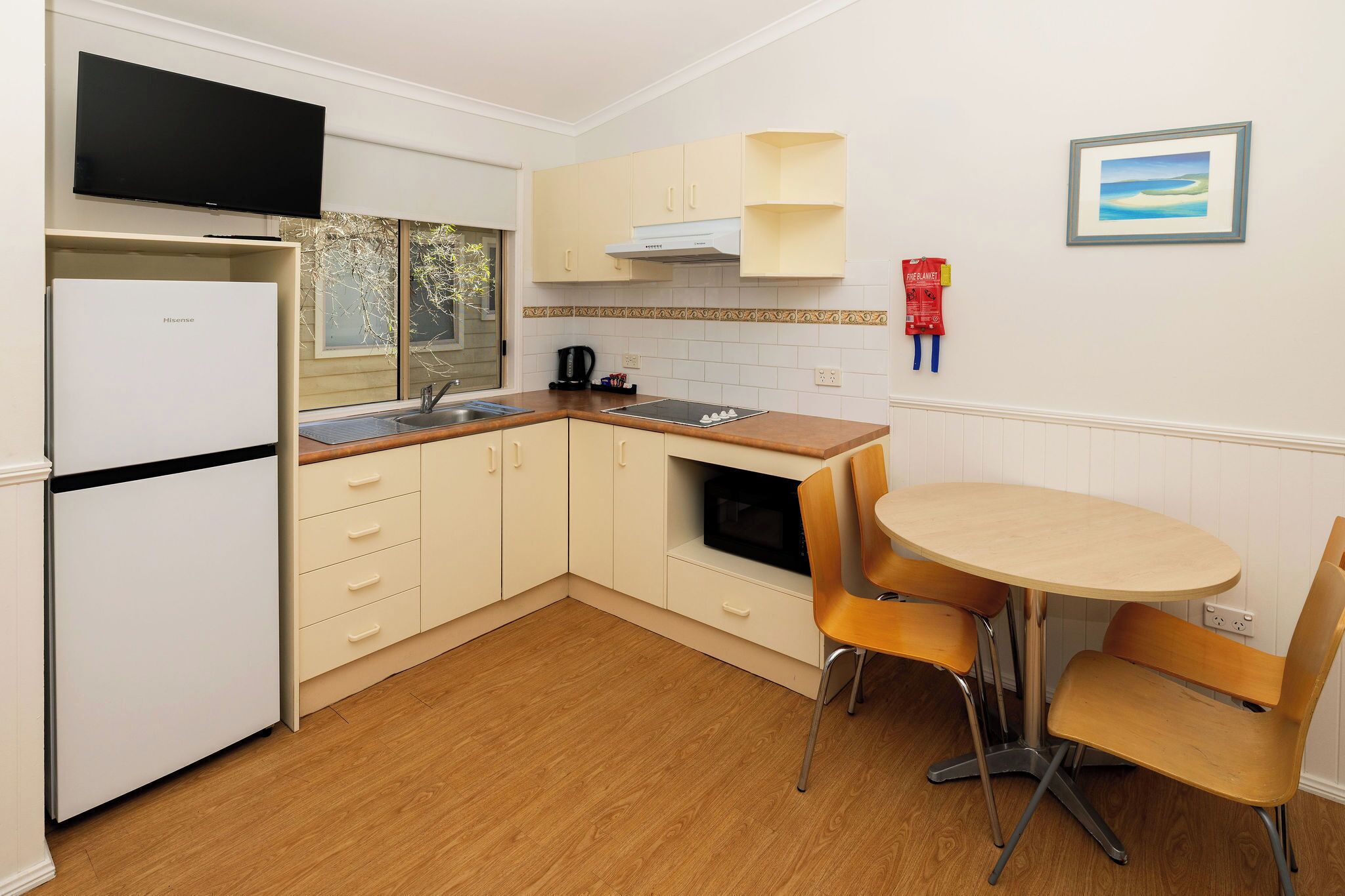 A compact kitchen with a refrigerator, microwave, and sink. There is a small dining table with two chairs.