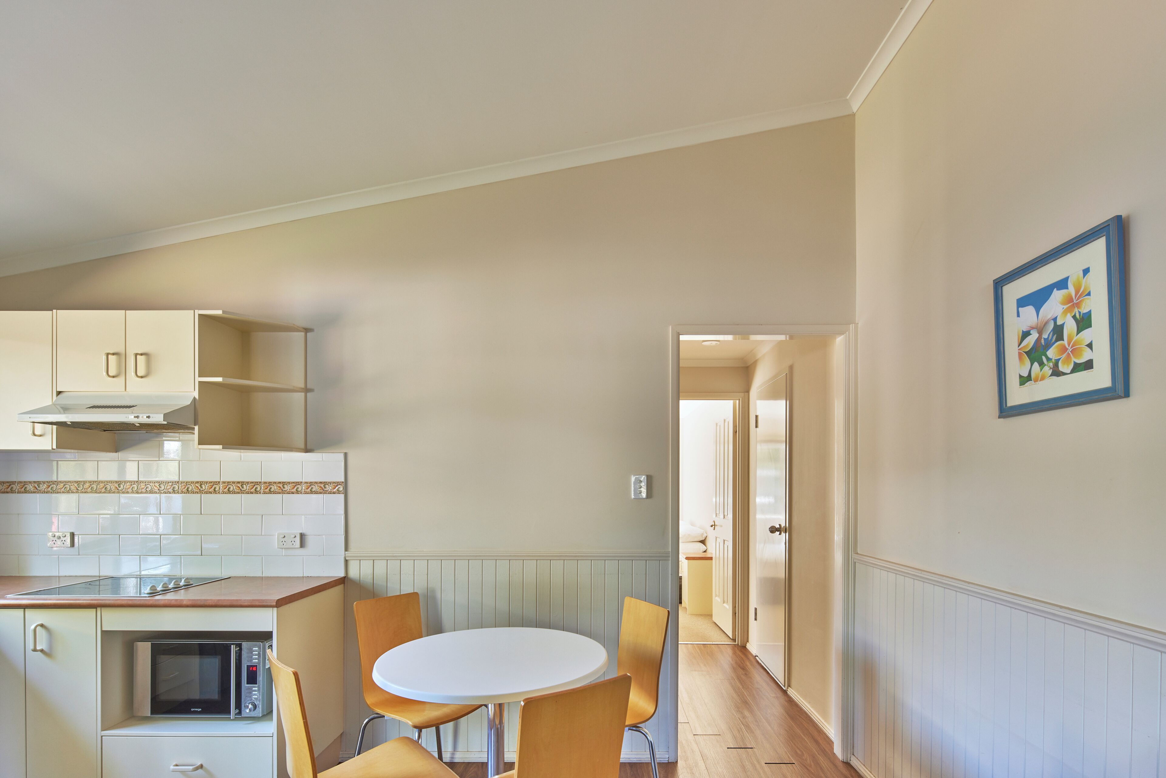 A kitchen with a microwave, a stove, and a dining area with a table and chairs.