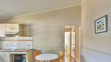 A kitchen with a microwave, a stove, and a dining area with a table and chairs.