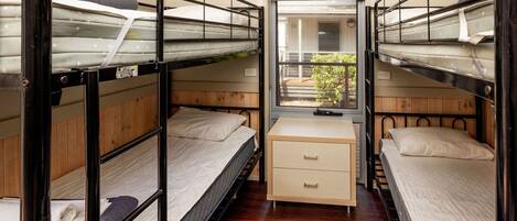 Habitación pequeña con literas, un escritorio y ventana con vistas al exterior.