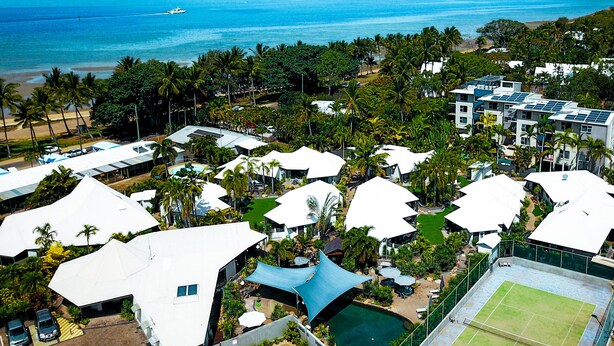 Ein Resort mit mehreren Gebäuden mit weißen Dächern, einem Pool und einem Tennisplatz.