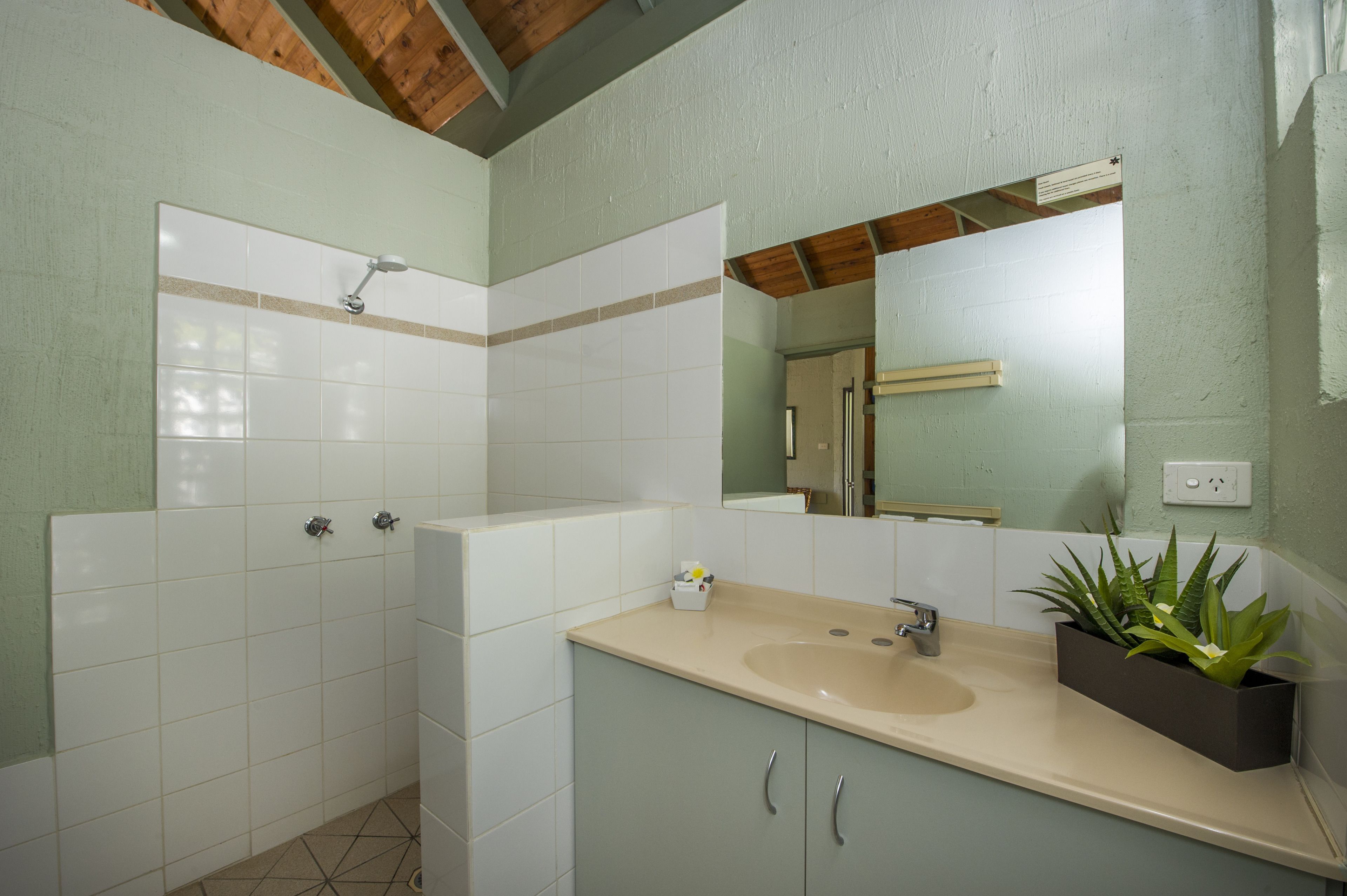 A bathroom with white tiles, a beige sink, and a mirror.