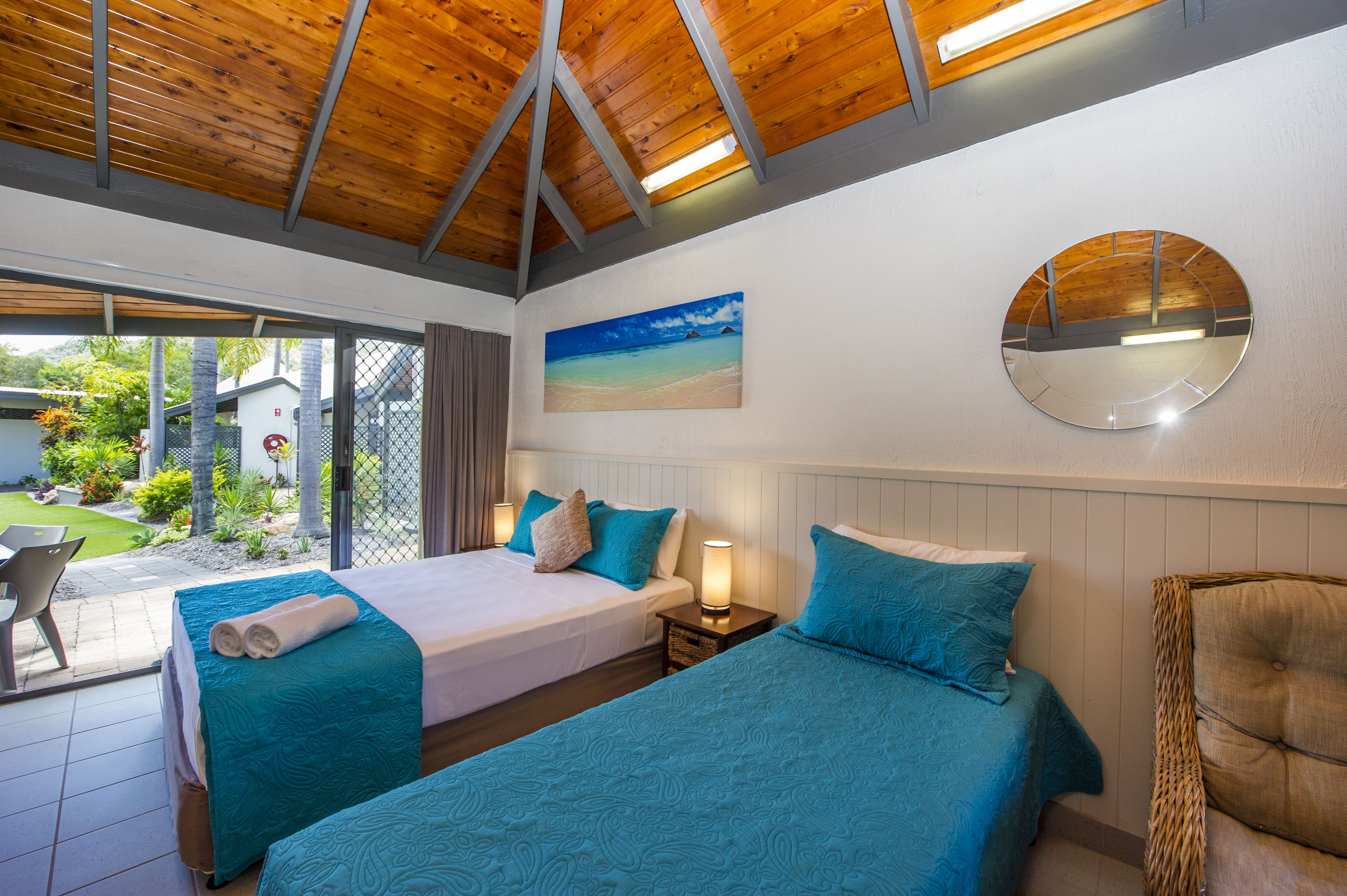 A hotel room with two beds, a large window, and a view of the outdoors.