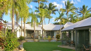 Ein Resort mit mehreren bungalowartigen Gebäuden, jedes mit überdachter Terrasse und Sitzgelegenheiten im Freien.
