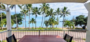 Un espacio de estar al aire libre cubierto con vistas al mar y palmeras.