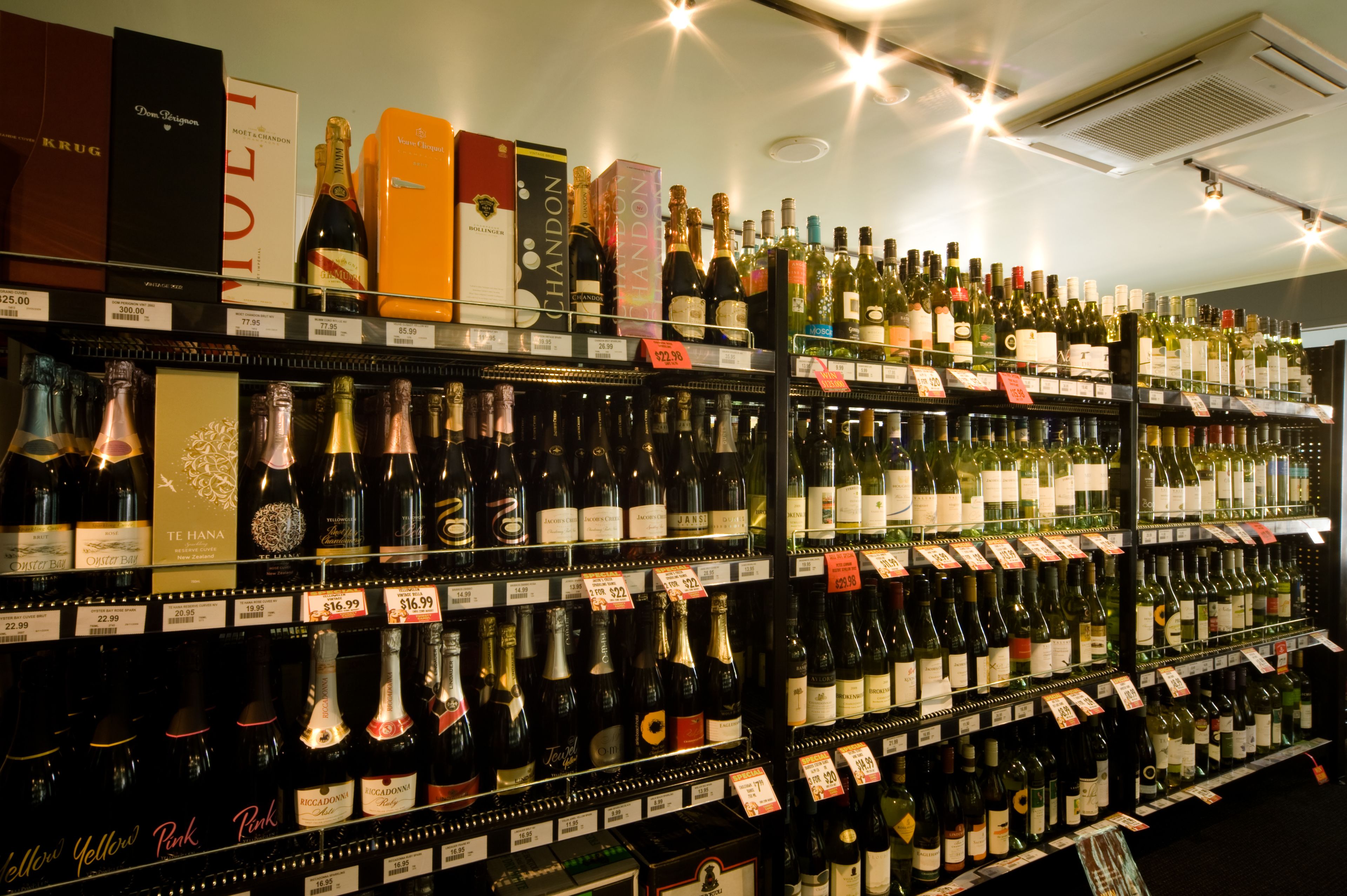 Uma loja de vinhos com prateleiras repletas de garrafas variadas, cada uma com etiqueta de preço.