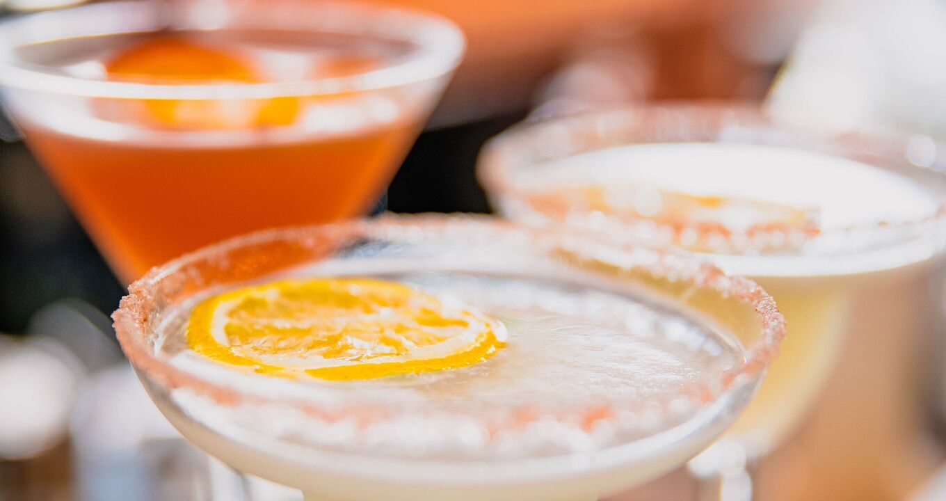 Een close-up van drie cocktails met een zoutrandje en een oranjeschijfje.