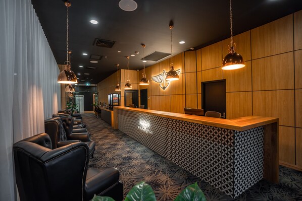 A hotel reception area with leather seating, a patterned carpet, and pendant lighting.
