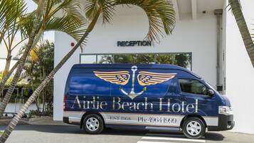 A van parked in front of a building with a reception sign, indicating it is likely a hotel.