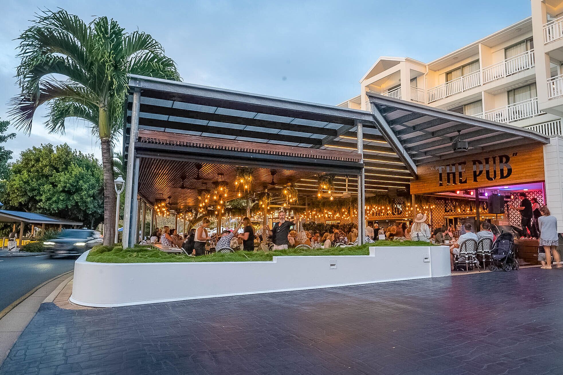 A restaurant with an outdoor seating area, covered by a metal roof, and a sign reading "THE PUB".