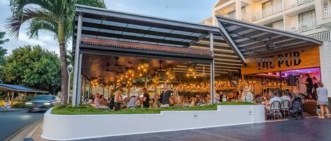 A restaurant with an outdoor seating area, covered by a metal roof, and a sign reading "THE PUB".