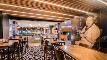 A modern bar area with wooden ceiling, bar stools, and a patterned floor.