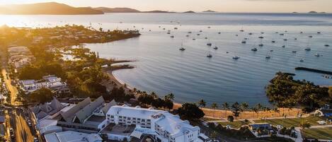An aerial view of a coastal area with a marina, a hotel, and a road.