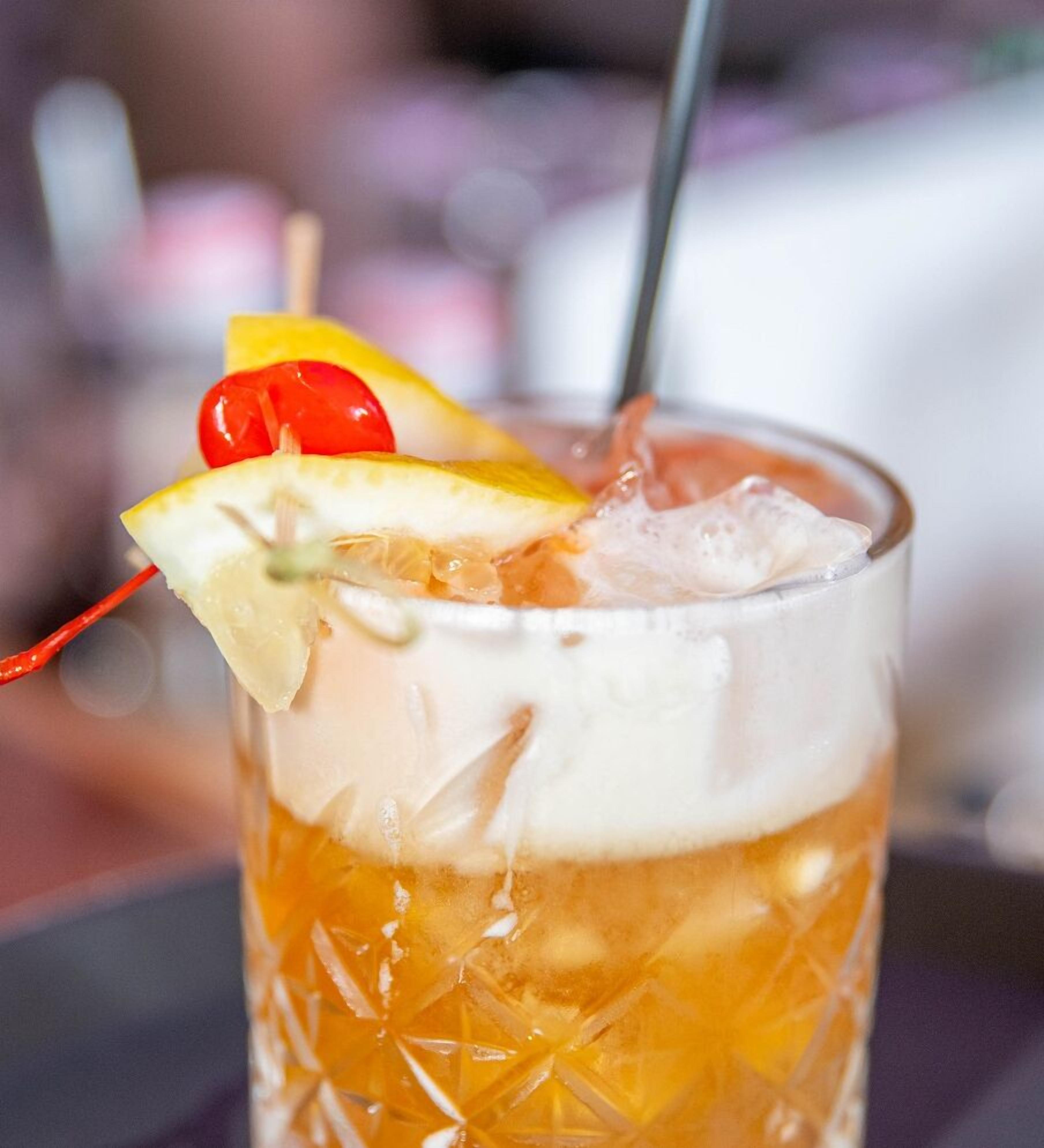 A glass with a layered beverage, ice, and garnishes.