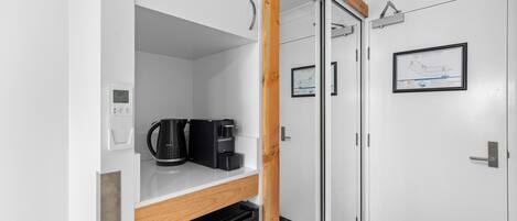 Una cocina compacta con cafetera, lavavajillas y un armario.