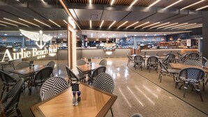 Un restaurante moderno con barra, techo de madera y sillas estampadas.