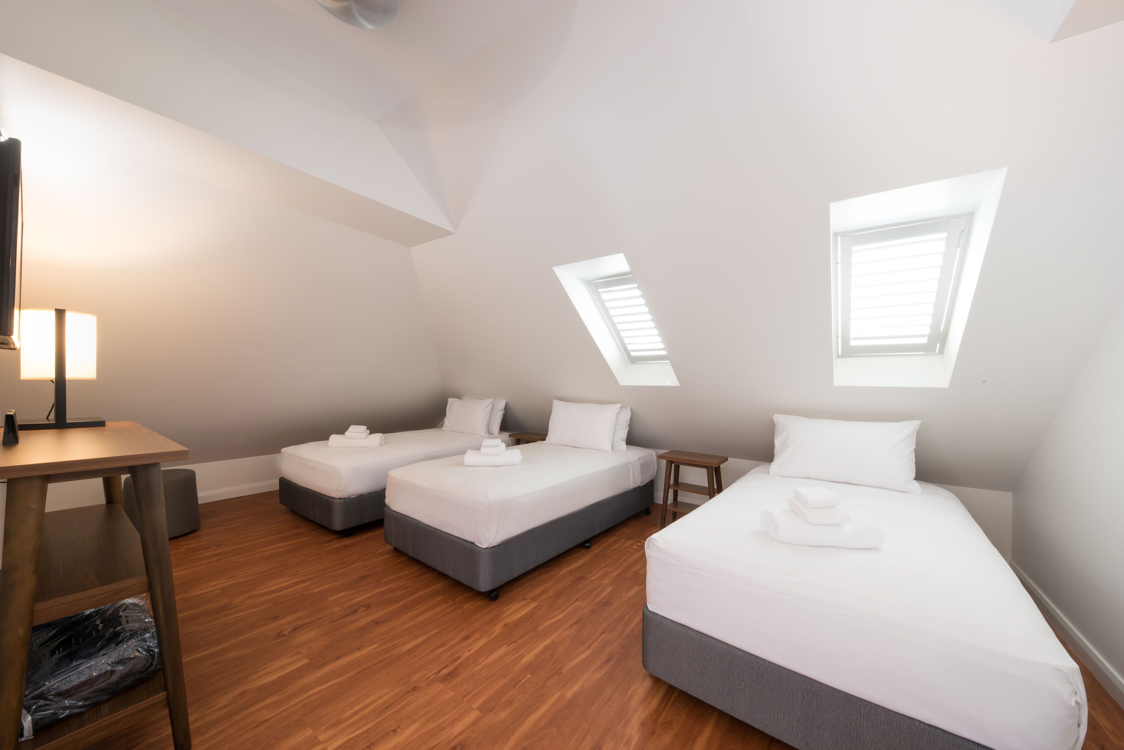 Een moderne, goed verlichte kamer met twee enkele bedden, een bureau en een klein tafeltje.