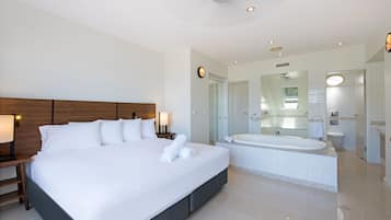 A modern hotel room with a large bed, a separate bathroom including a bathtub, and a walk-in shower.