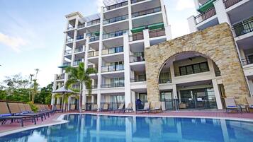 Un hotel de varios pisos con piscina, mobiliario exterior y un arco de piedra.