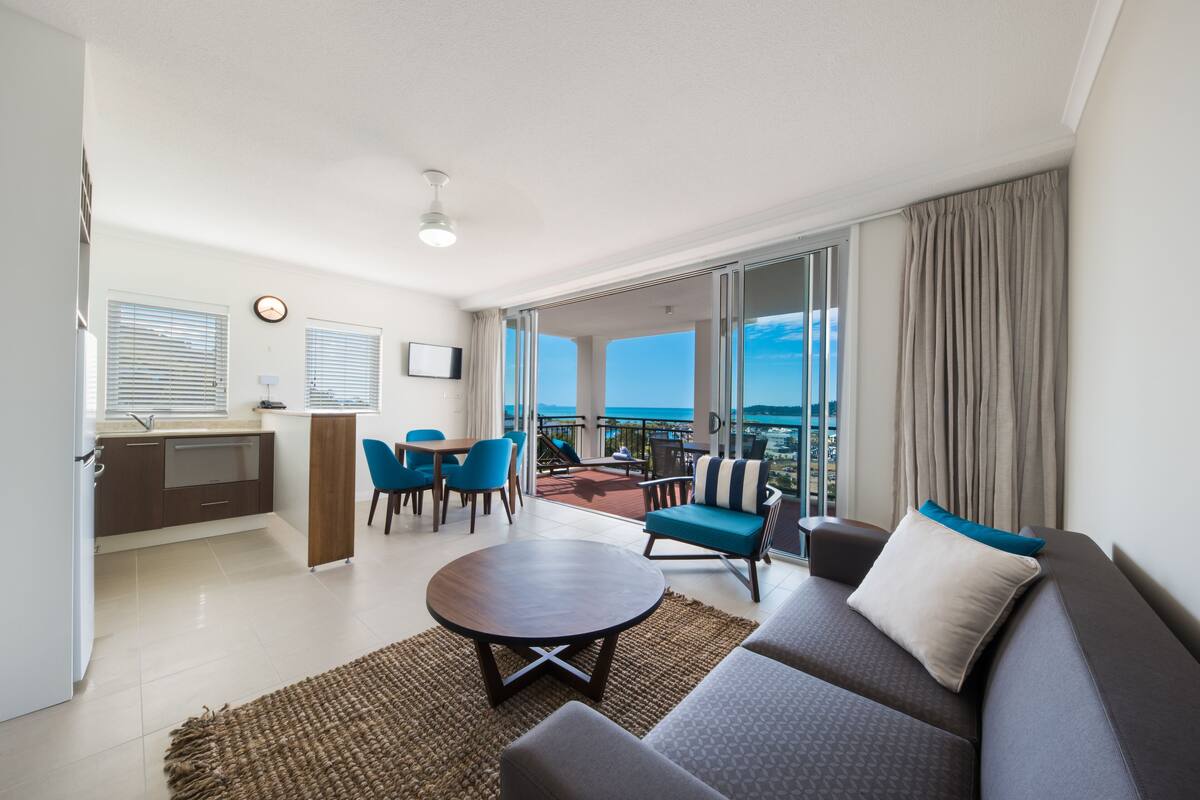 Una habitación de hotel moderna con balcón, comedor y sofá.