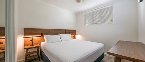 Un dormitorio con cama, mesitas de noche, un escritorio y un ventilador de techo.