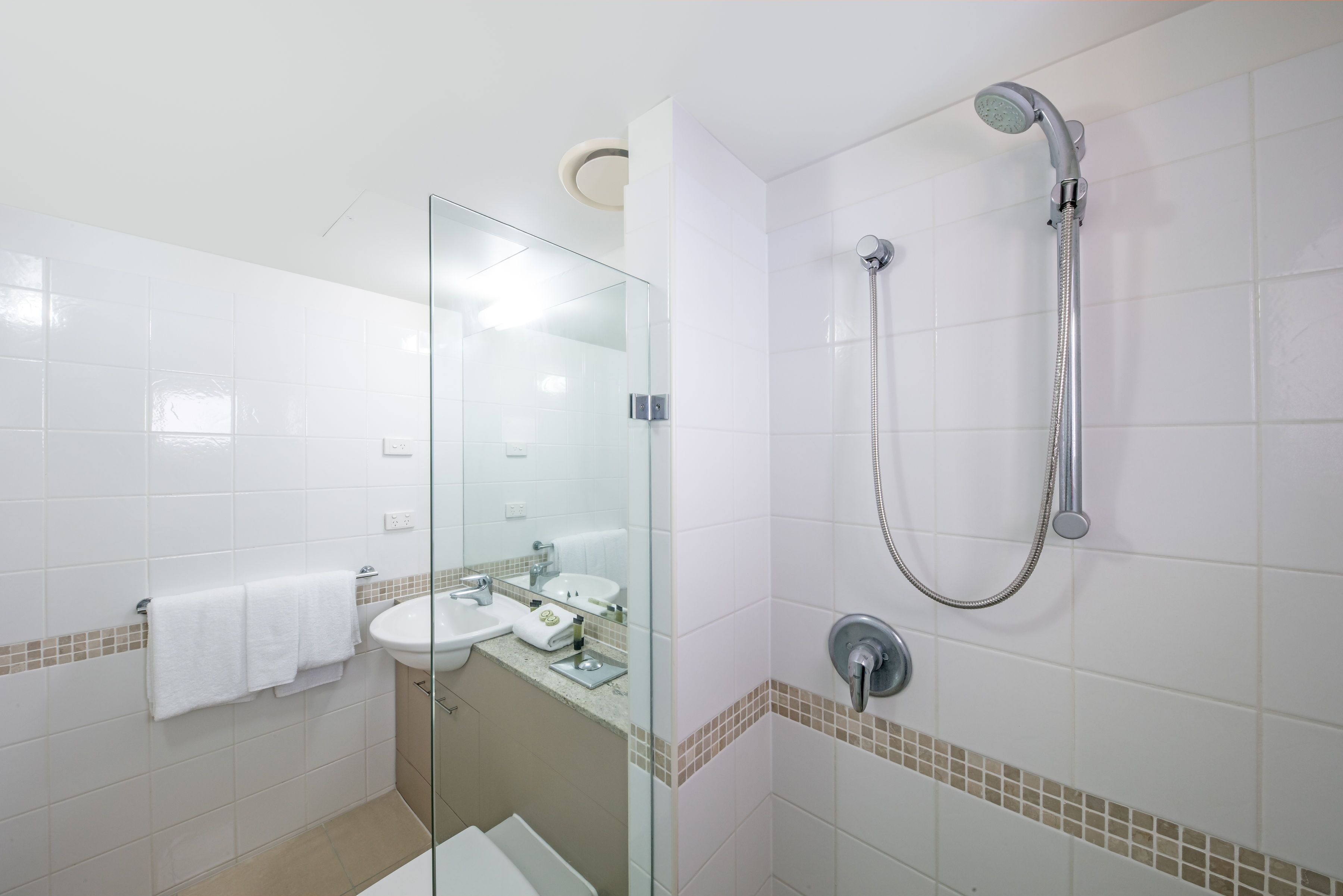 Une salle de bain moderne avec une douche à parois de verre, un lavabo avec un miroir et un porte-serviettes.