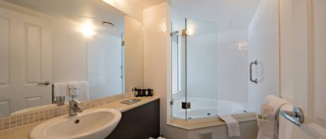 Un baño moderno con un lavamanos grande, espejo, cabina de ducha de vidrio y bañera.