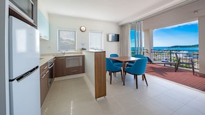 Una cocina moderna con comedor, televisor y vista al mar.