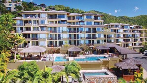 A multi-story hotel with balconies, a swimming pool, and tropical landscaping.