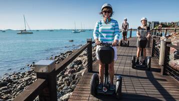 Un muelle de madera junto al mar, con gente circulando en segways.