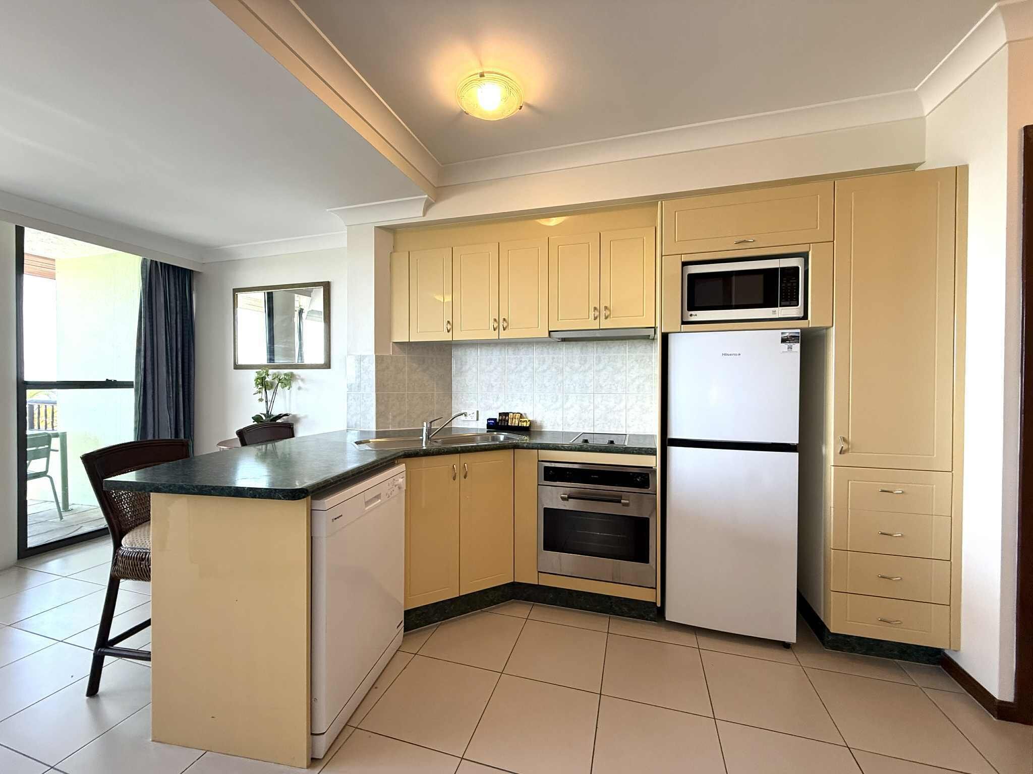 A compact kitchen with a central island, a microwave, a refrigerator, and a dishwasher.