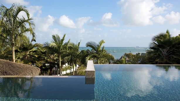 A clear view of an infinity pool with a view of the ocean and boats.