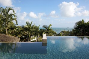 A clear view of an infinity pool with a view of the ocean and boats.