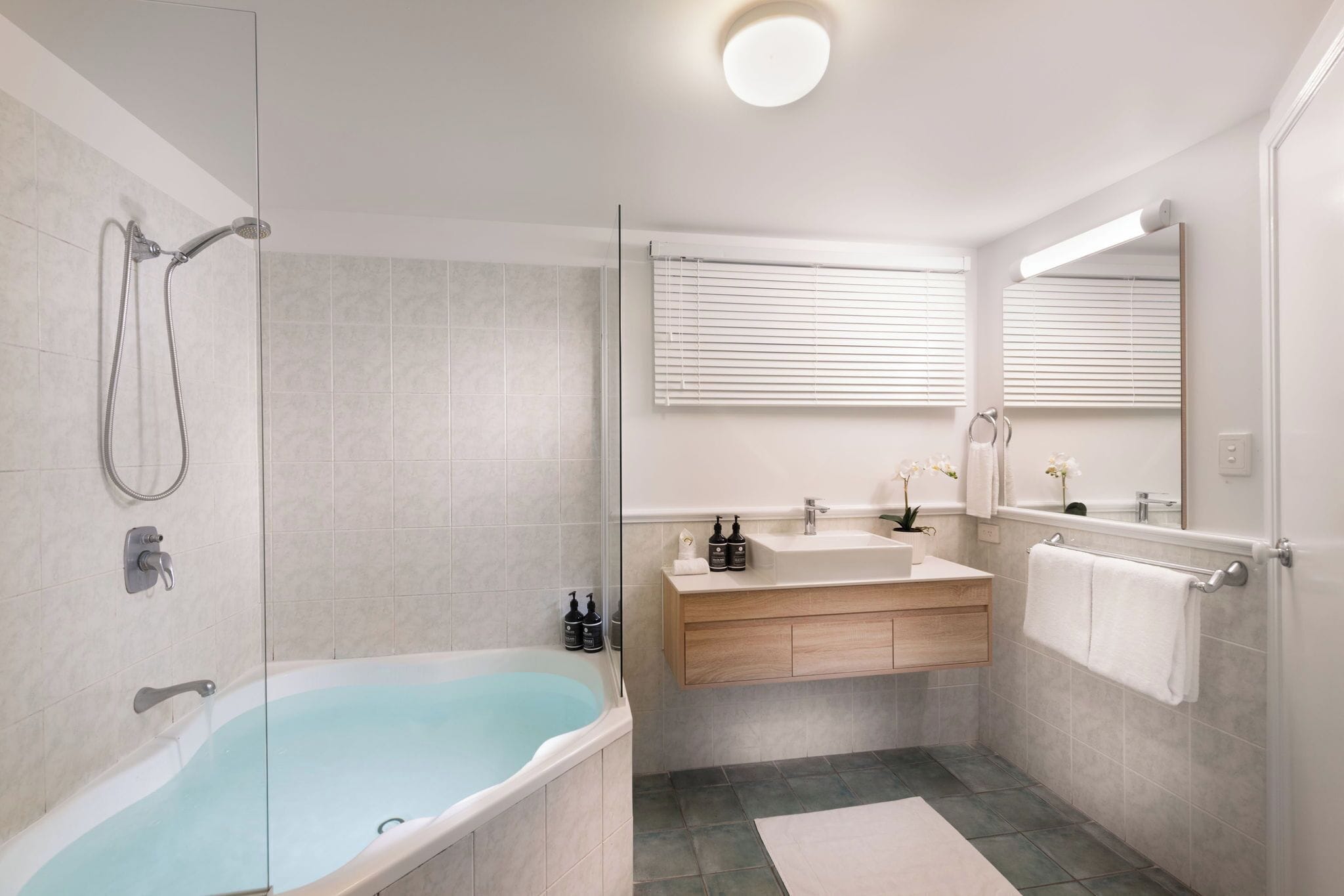 A modern bathroom with a glass-enclosed shower, a freestanding bathtub, and a vanity with two sinks.
