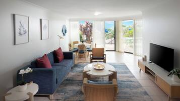 A modern living room with a sofa, chairs, a TV, and a balcony with a view.