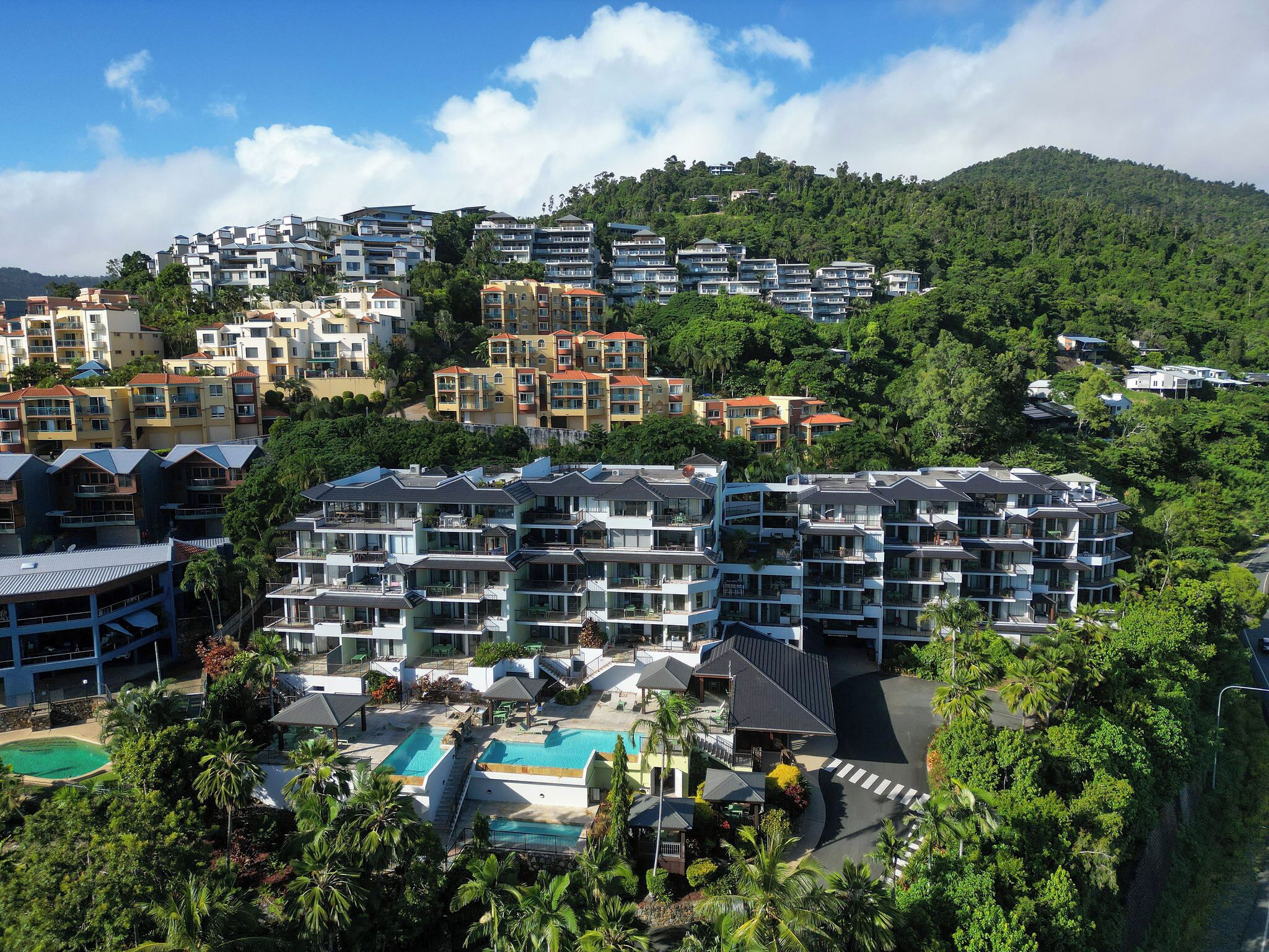 Un resort con varias edificaciones, piscina y exuberante vegetación.